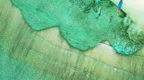 Rompeolas natural, arrecife de coral que rodea la isla tropical. Aérea, revelando barcos flotantes a