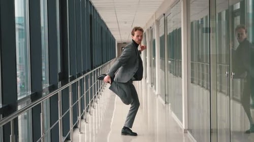 Happy Successful Businessman Dancing In a Crazy Way at indoor modern office building. Funny dance of