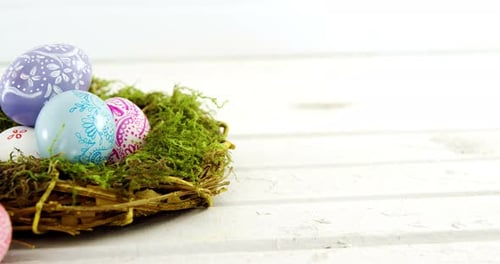 Painted Easter eggs in the nest on wooden surface