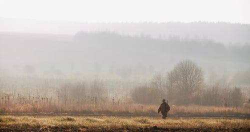 Man Walking in Foggy Rural Grassy Field