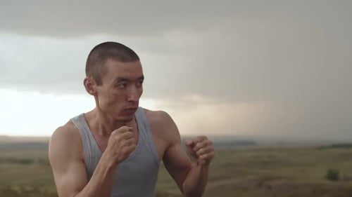 Asian Athlete Man Practice Series of Boxing Punches Air Outdoor Cloudy Weather Side View