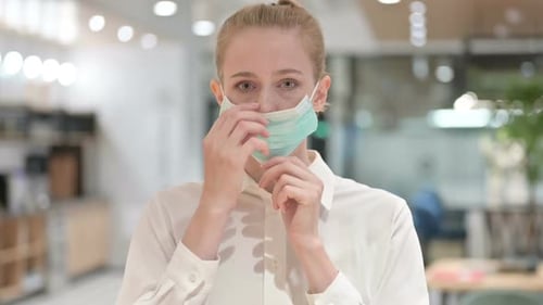 Young Woman Puts on Surgical Mask Indoors
