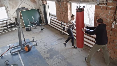 Woman Boxing with Trainer in Bright Gym