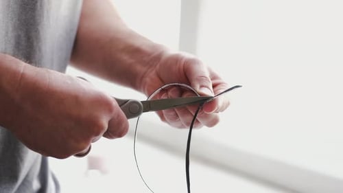 Man cutting black material with scissors in bright light