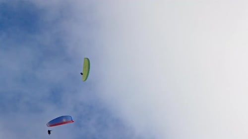 People Try Paragliding Flying with Parachutes Against Clouds