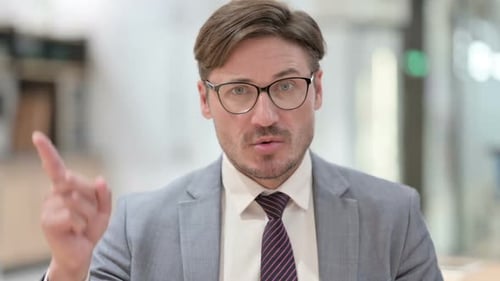 Porträt eines seriösen Geschäftsmannes, der per Fingerzeichen Nein sagt