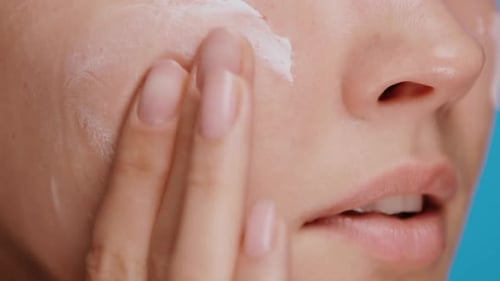 Close-up of Woman Moisturizing and Massaging Cheek and Under Eye Zone with Cream