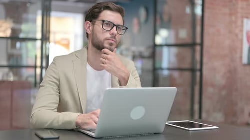 Young Man with Laptop Thinking