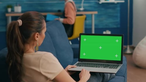 Woman Types on Laptop with Green Screen on Couch