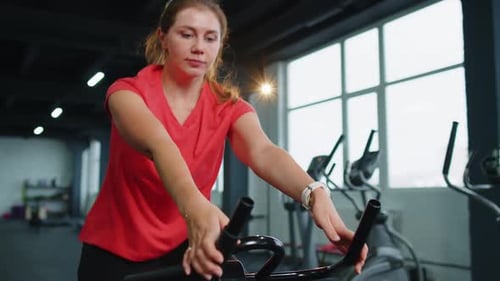 Woman Exercising on Stationary Bike at Gym