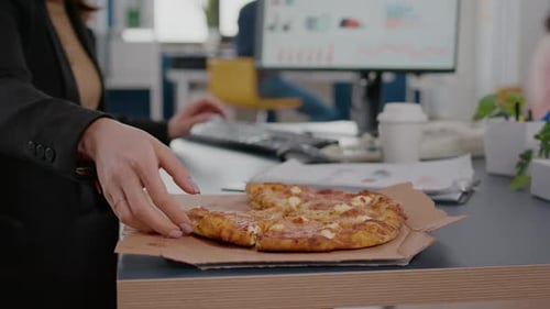 Young Woman Enjoying Pizza Lunch at Office Desk