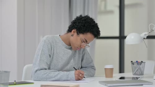 Young Adult Writing at Desk in Workplace