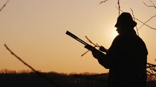 Silhouette eines männlichen Jägers, der im Wald jagt, zielt