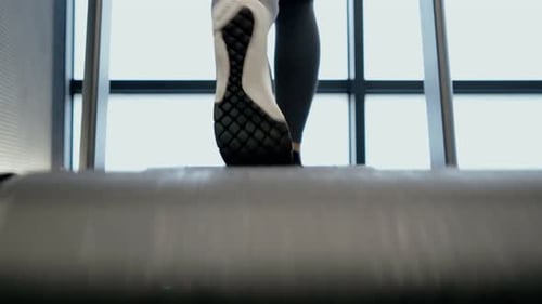Woman Legs Running on Treadmill in Modern Gym
