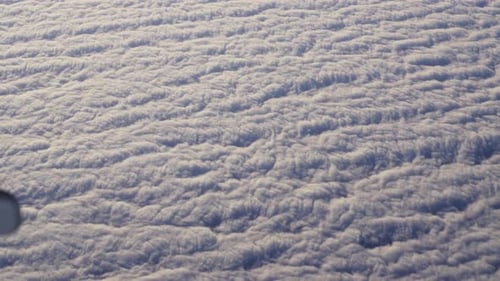 View Through Plane Window on Beautiful Sea of White and Fluffy Clouds