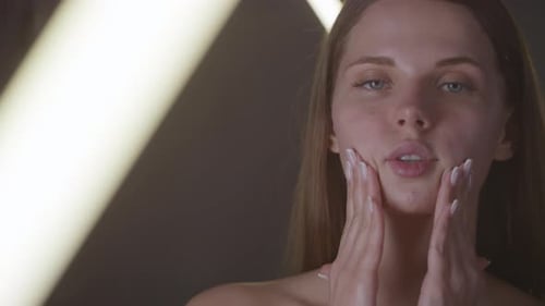 Woman Massaging Cream Into Her Face in Close Up