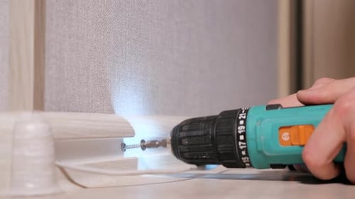 Hand Using Electric Screwdriver to Screw in Screw