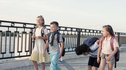 Happy four young students walking after school and talking.