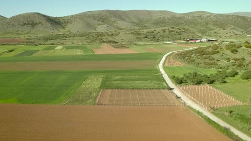 Aerial view of grass fields surrounded by vegetation and hills.