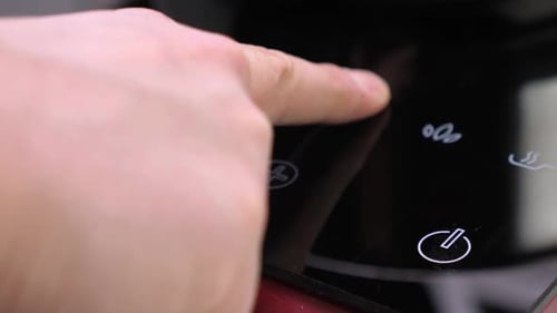 Finger Touching Digital Controls on Modern Stovetop
