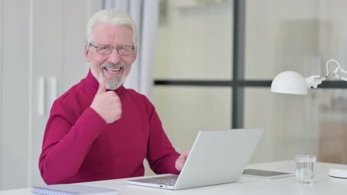Senior Man Gives Thumbs Up at His Desk