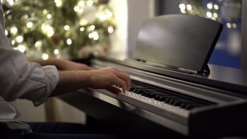 Un pianiste musicien joue du piano numérique à côté d'un sapin de Noël