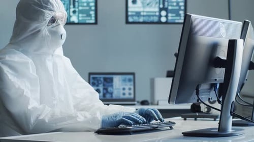 Scientist in Hazmat Suit Typing at Computer in Lab
