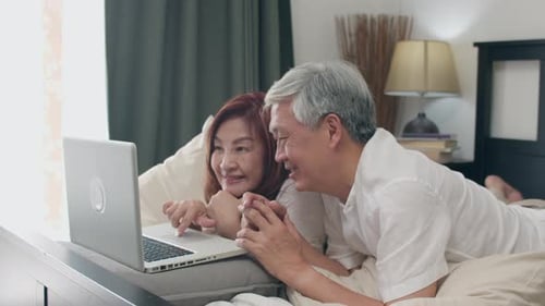 Happy Couple Relaxing in Bed Using Laptop