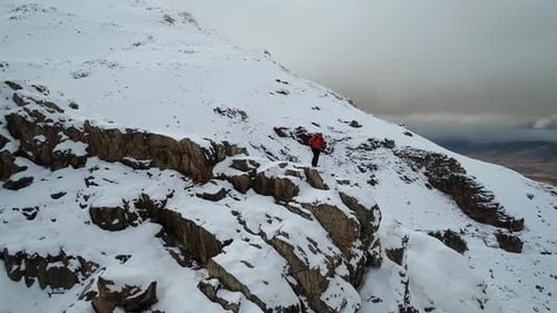 Hiker on Snowy Mountain Peak in Winter Landscape