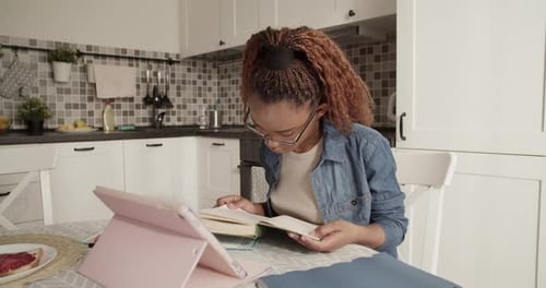 Young Adult Studying with Book and Tablet at Home