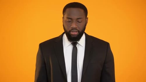 Man in Suit Gesturing on Orange Background