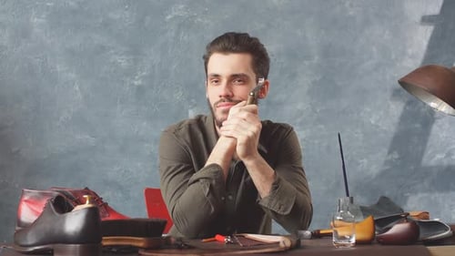 Man Sitting at Desk in his Shoe Repair Workshop