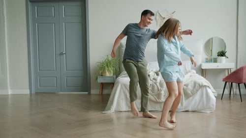 Playful Couple Dancing Barefoot in Bedroom Together