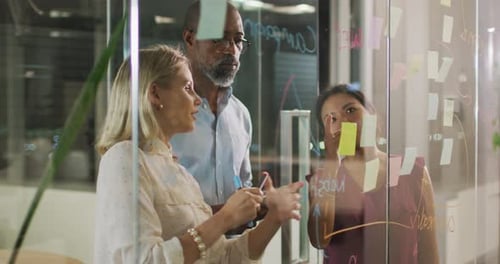 Professional businesspeople discussing together over a glassboard in modern office in slow motion
