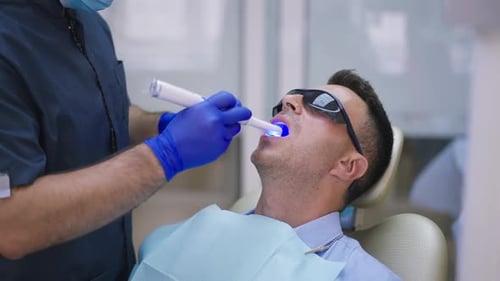 Dentist Using Dental Curing Light on Patient