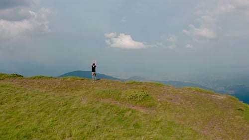 Aerial Drone View. Flying Around Young Man Standing on Top of the Mountain at Sunset V2