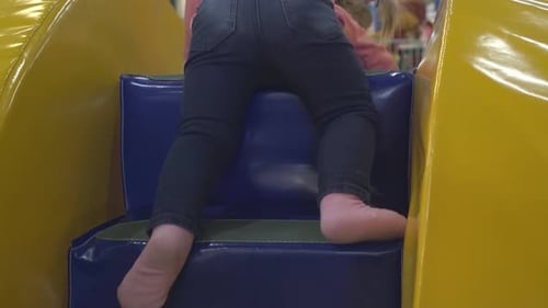 Une petite fille grimpe sur une colline gonflable multicolore joue dans une salle de jeux pour enfants
