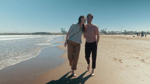 A Happy Couple Walking Down the Beach Barefoot Holding Hands
