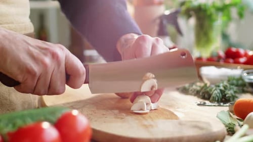 Adult Slicing Mushroom with Knife in Kitchen