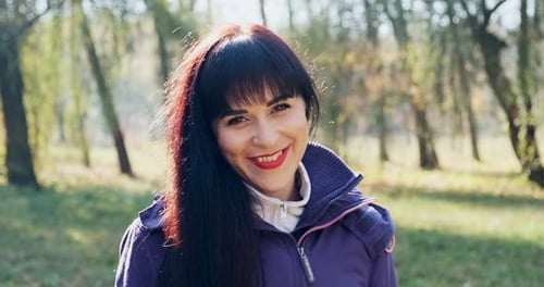Portrait of Young Attractive Brunet Woman Who Smiling and Looking at the Camera on Autumn Park