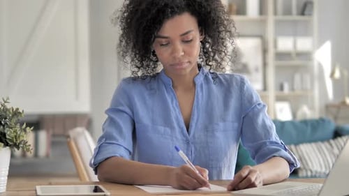 Woman Writing at Desk in Home Office