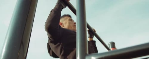 Strong Man Doing Pull-Ups on Horizontal Bar Outdoors