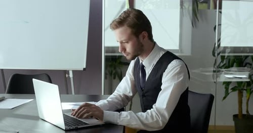 Serious Business Man Working at Laptop Sitting at Office Table. Concentrated Guy Programmer
