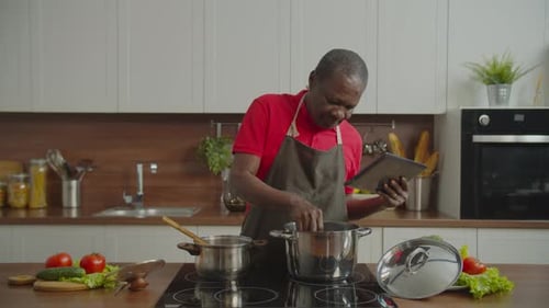 Man Cooking at Home Following a Recipe on Tablet
