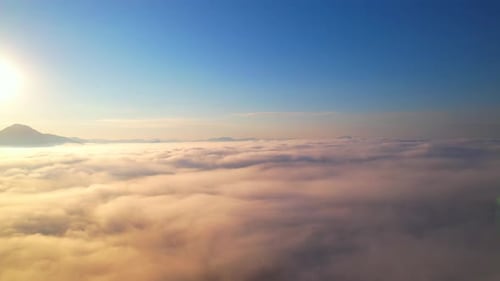 4K Aerial view flying in fog. the sun is hidden behind the clouds at sunset fog.