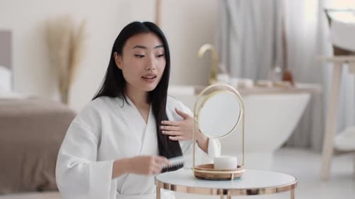 Elegant Woman Combing Long Black Hair in Bathroom