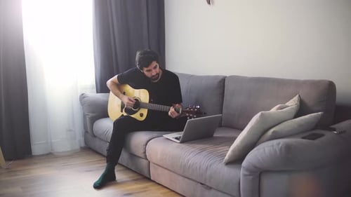 Young Adult Plays Guitar on Couch