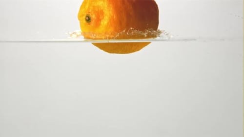 Super Slow Motion One Fresh Lemon Falls Into the Water with Splashes and Air Bubbles