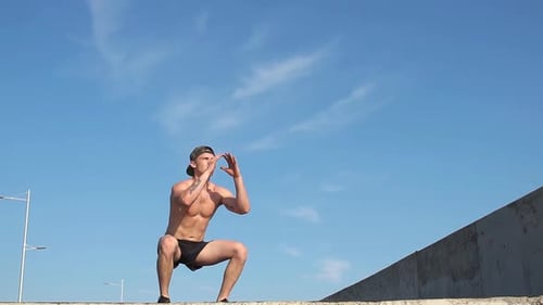 Athletic Man Performing Squats Outdoors in Sunlight