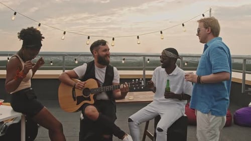 Friends Gather For Rooftop Party With Guitar Music